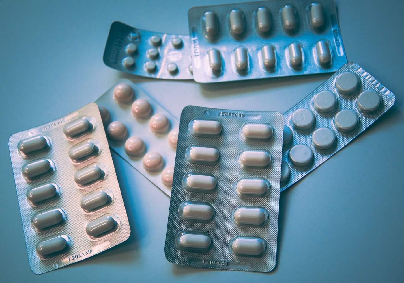 Medication blister packs arranged on a clinical blue surface.